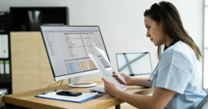 Billing professional reviewing clinical paperwork at a desk